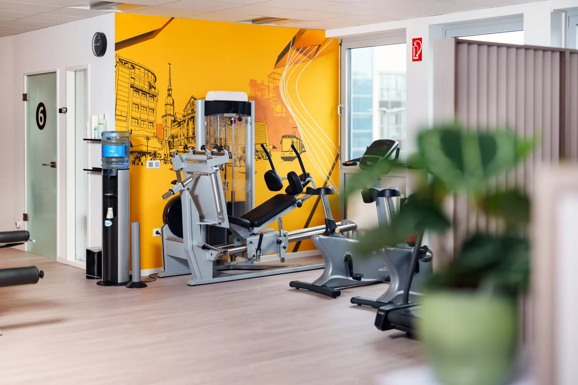 Impression aus der Praxis - Scholz & Abela - Physiotherapie Dortmund Teilansicht der Trainingsfläche bei Scholz & Abela mit Fensterfront und Beinpresse
